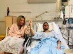 Kidney recipient Matt in a hospital bed with his mother in a chair beside him holding his hand