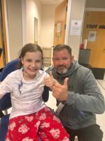 Paul and Grace in hospital giving a thumbs up