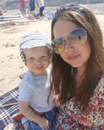 Living kidney donor Sara with her son Joseph, who she donated a kidney to. they are sitting on a blanket at the beach, smiling towards the camera.